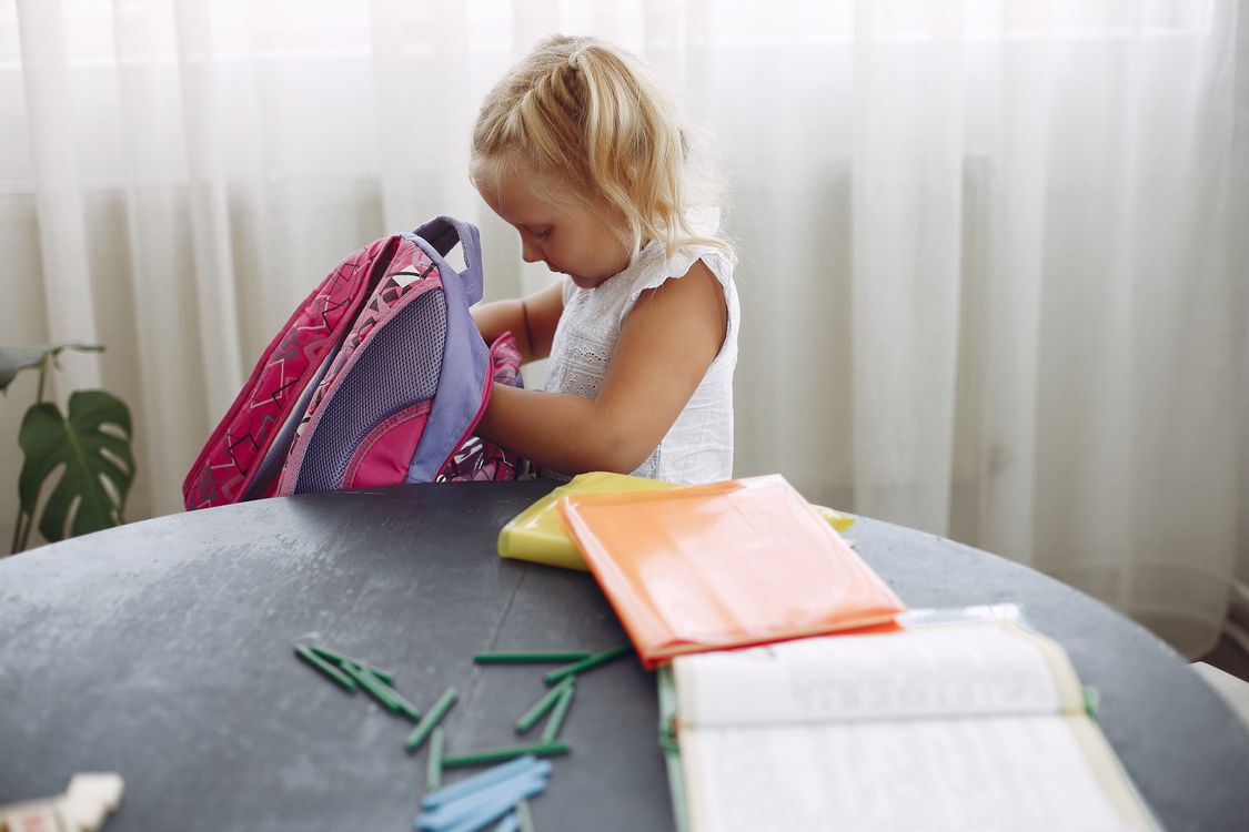Enfant préparant son cartable avec ses fournitures scolaires pour la rentrée 2026